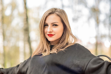 Naklejka premium Young pretty elegant lady posing near colourfull tree at autumn