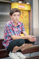 teenage boy crouching on a bench