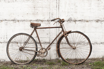 Fototapeta na wymiar Antique or retro oxidized bicycle outside on a concrete wall
