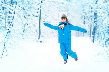 Fototapeta na wymiar Funny boy jumping in a snowy park
