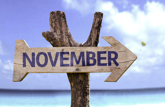 November wooden sign with a beach on background