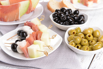 Delicious melon with prosciutto on plate on table close-up