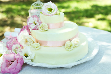 Fototapeta na wymiar Beautiful wedding cake with flowers on table, outdoors