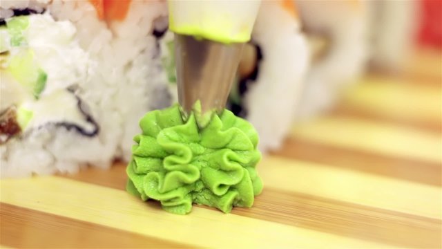 Adding wasabi on plate with sushi