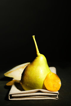 Ripe tasty pear on wooden table, on dark background