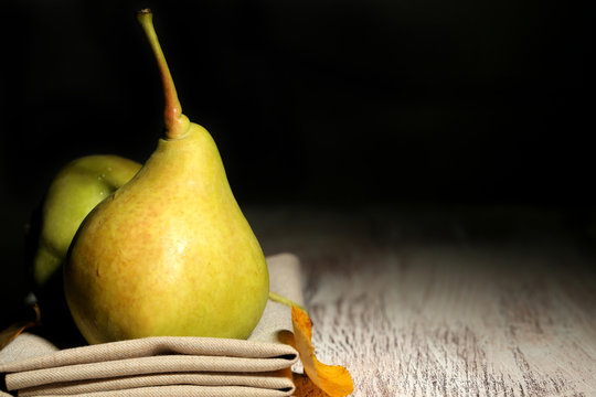 Ripe tasty pears on wooden table, on dark background