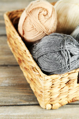 Obraz premium Knitting yarn in basket, on wooden background