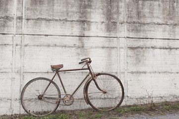 Fototapeta na wymiar Antique or retro oxidized bicycle outside on a concrete wall