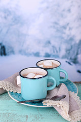 Cups of tasty hot cocoa, on wooden table, on light background