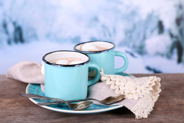 Cups of tasty hot cocoa, on wooden table, on light background