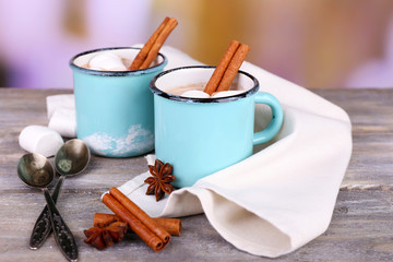 Cups of tasty hot cocoa, on wooden table, on light background