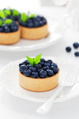 Tartlets with cream and blueberries, selective focus