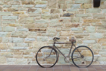 Fototapeta na wymiar Antique or retro oxidized bicycle outside on a stone wall