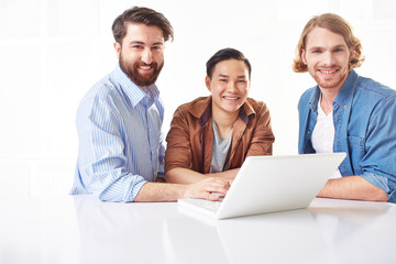 Three handsome young men using a laptop