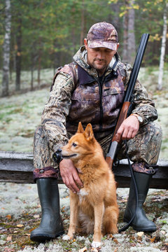 hunter with a dog sitting in the forest