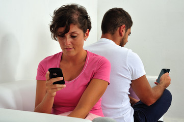 Couple back to back with smartphone