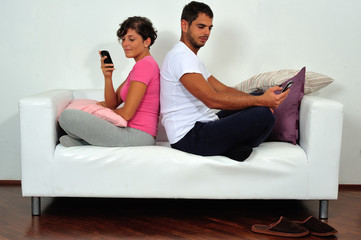 Couple back to back with smartphone on sofa