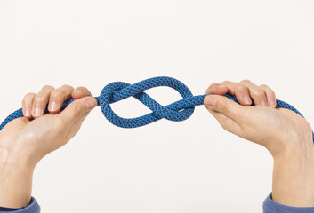 Female hands holding a climbing rope making a secure node
