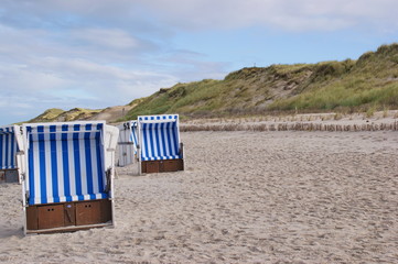 Leere Strandkörbe mit Dünen