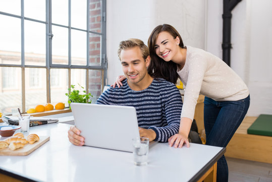 glückliches junges paar schaut auf laptop