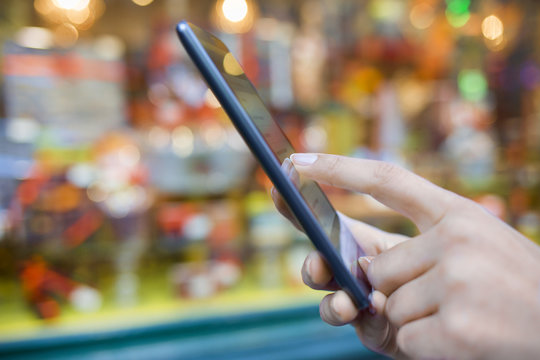 Woman using her mobile phone in front of a storefront gift