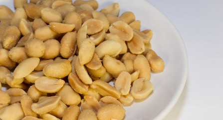 Peanuts on a white plate on a white background