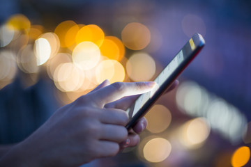 Woman using her mobile phone , city skyline night light