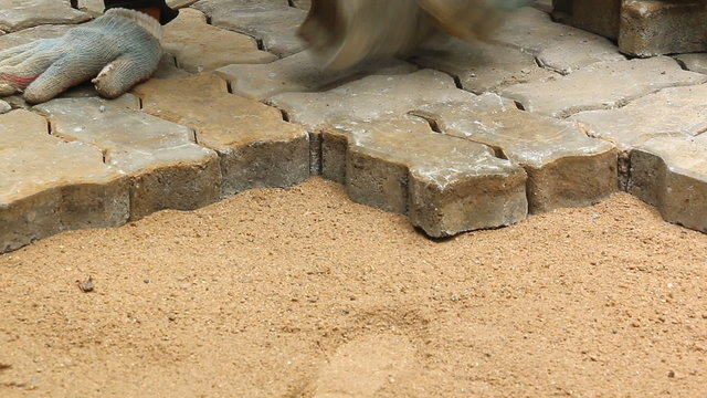 worker installing old cobblestone block
