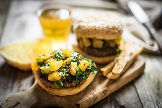 Homemade burgers with fries on wooden background