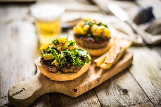 Homemade burgers with fries on wooden background
