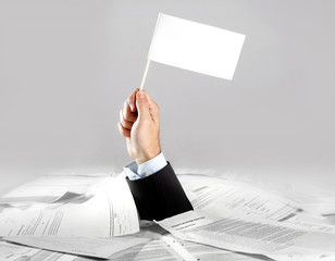 Hand of  businessman holding white flag on paperwork desk