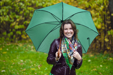 Woman with green umbrella smiling as raining