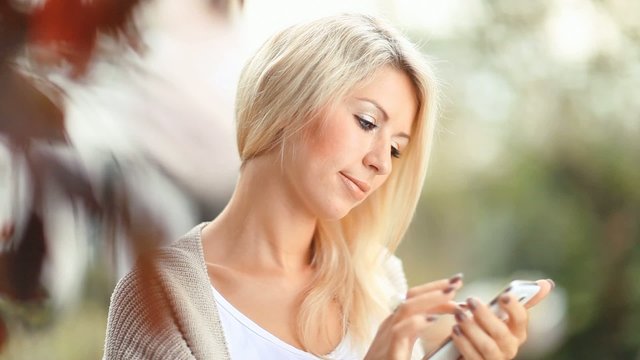 Beautiful woman with cell phone in the garden