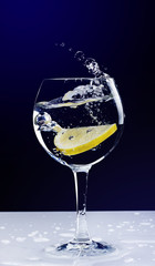 lemon falling in a glass with splash on black background