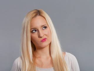 Thinking young woman looking up. Studio shot.