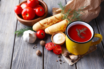 Homemade tomato juice in color mug, bread sticks, spices and
