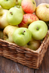 Ripe apples in basket on wooden table close-up