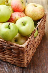 Ripe apples in basket on wooden table close-up