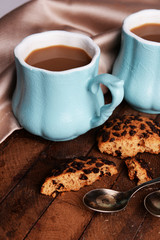 Cups of coffee with cookies and napkin on wooden table