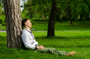 Obraz premium Happy young man relaxing in the park on sunny spring day
