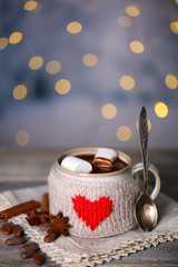 Cup of tasty hot cocoa, on wooden table, on shiny background