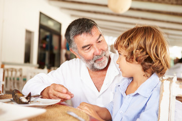 Obraz premium Grandfather And Grandson Enjoying Meal In Restaurant