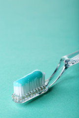 Toothbrush with blue toothpaste on color background