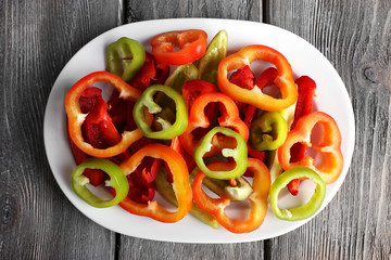 Sliced pepper on oval plate on wooden background