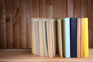 Books on wooden table on wooden wall background
