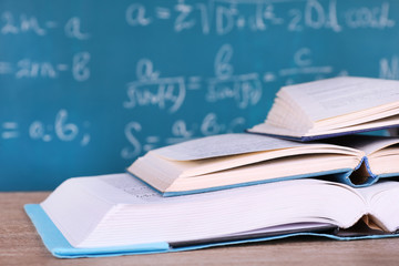 Books on wooden table on blackboard background