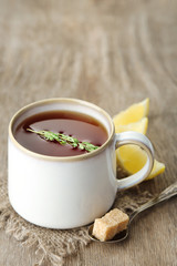 Cup of tasty herbal tea with thyme and lemon, on wooden table
