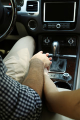 Loving couple holding hands in car close-up