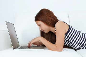 Beautiful little girl with laptop on sofa in room