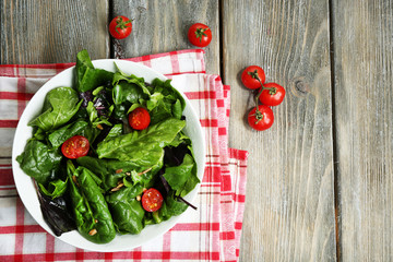 Fresh green salad in bowl on wooden table